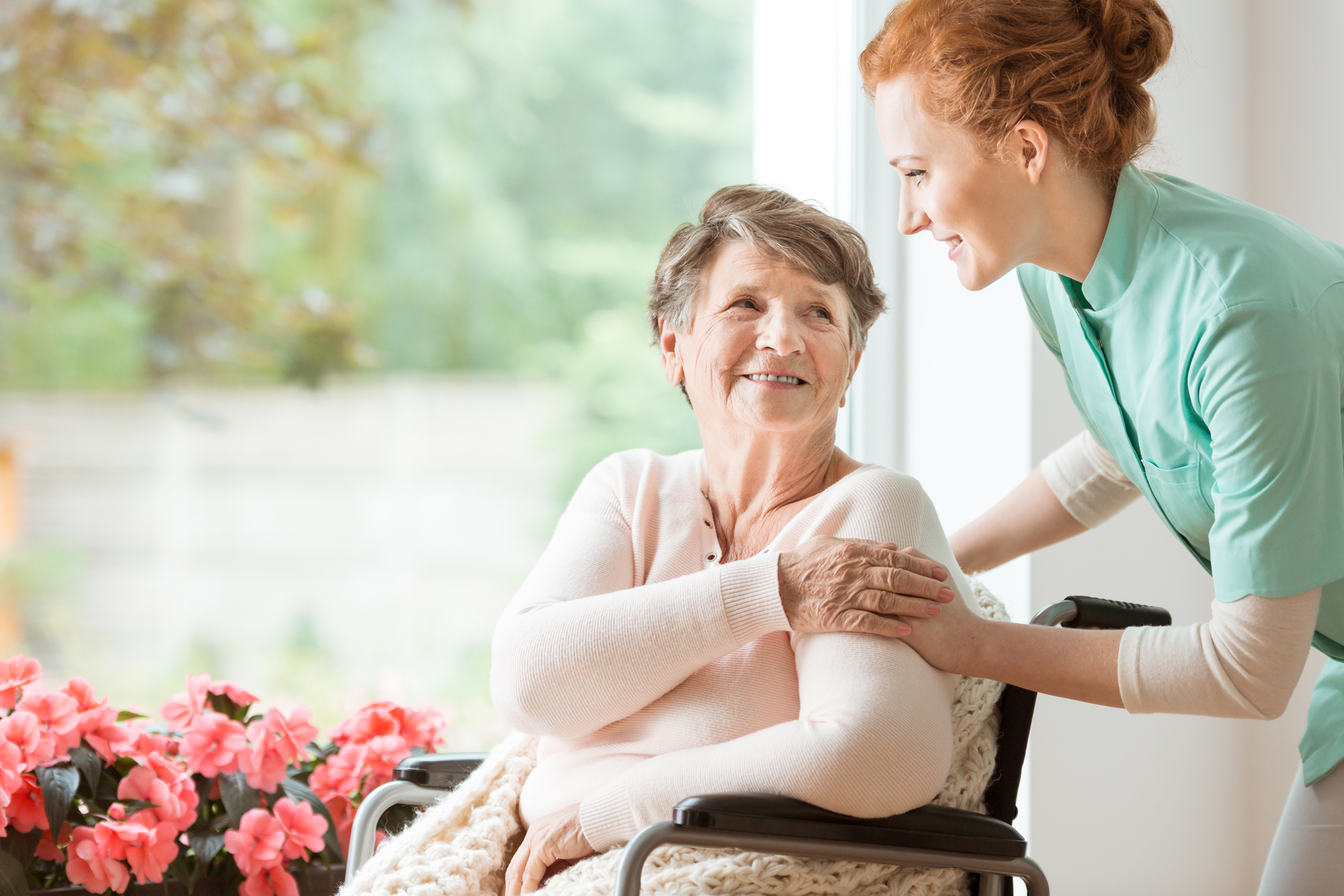 A nurse puts her hand on the shoulder of her patient, smiling as she explains What To Expect With Hospice