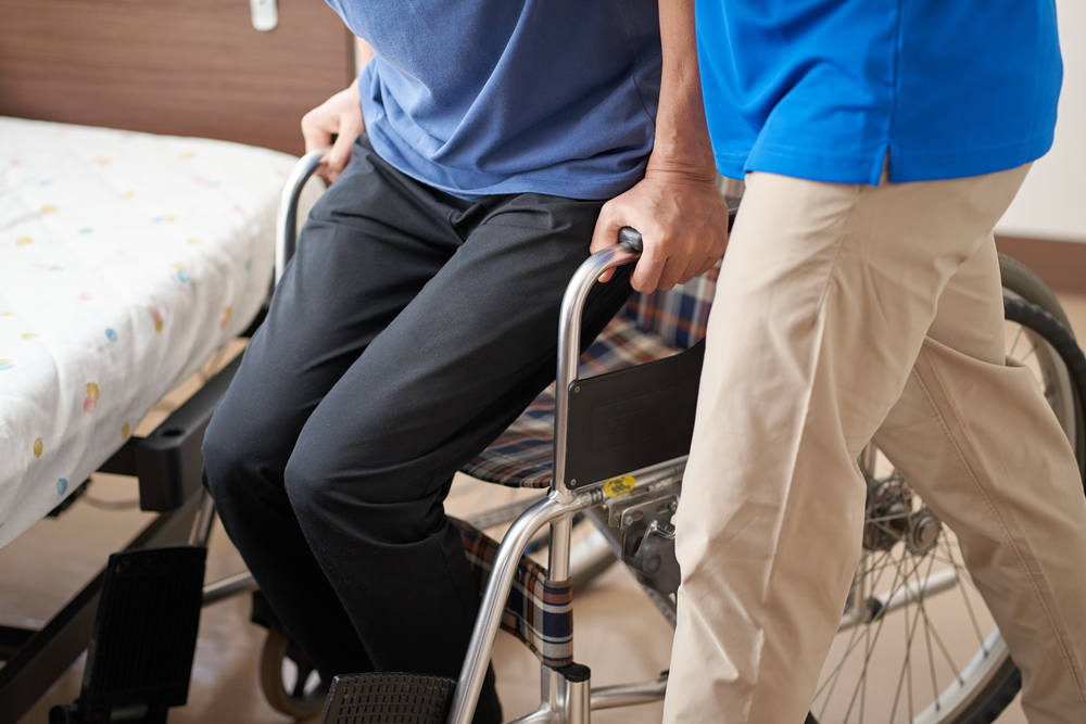 Helena, MT Cancer Patient Palliative Care giver helping a patient into a wheelchair from their bed