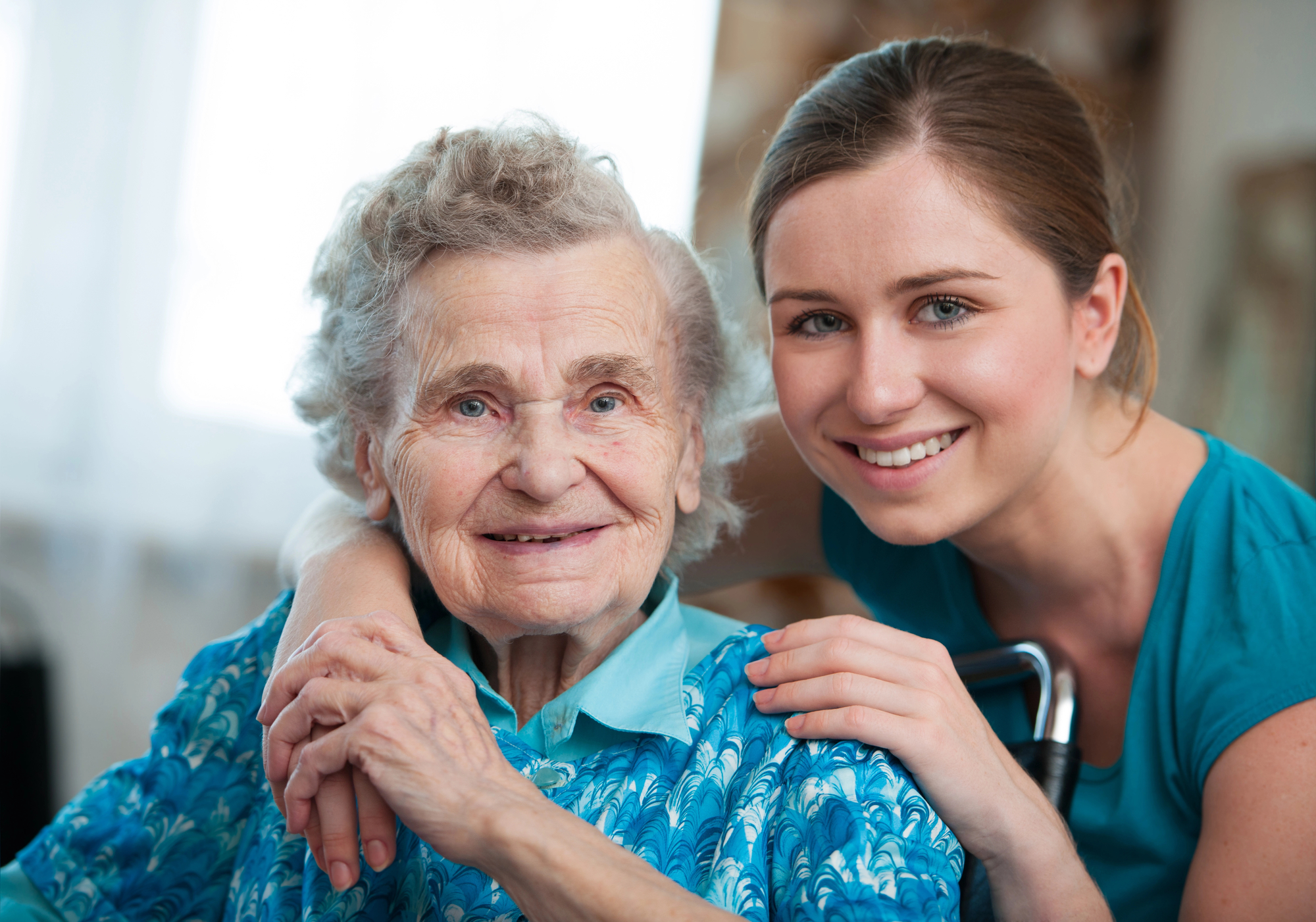 A nurse smiles with her arm around an elderly patient as they answer the question, what is hospice?